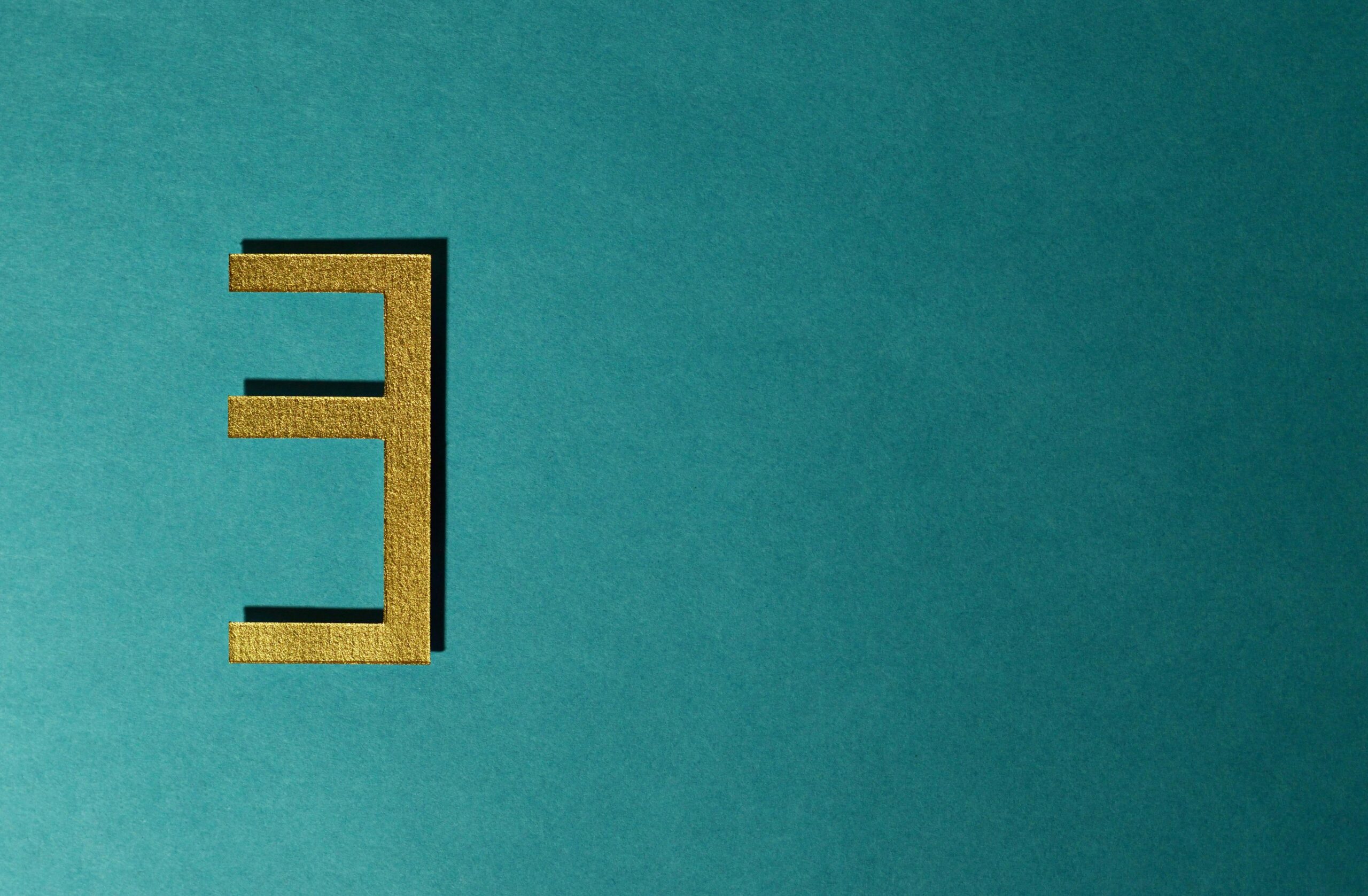 Abstract gold number three on a teal background with minimal design.